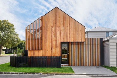 Immagine della facciata di una casa a schiera nera contemporanea a due piani con rivestimento in legno, tetto a capanna e copertura in metallo o lamiera