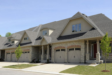 Modelo de fachada beige de estilo americano grande de dos plantas con revestimientos combinados y tejado a doble faldón