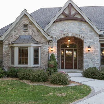 Huge traditional beige one-story stone exterior home idea in Milwaukee with a shingle roof