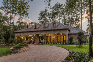 Example of a classic two-story brick house exterior design in Houston with a hip roof and a shingle roof