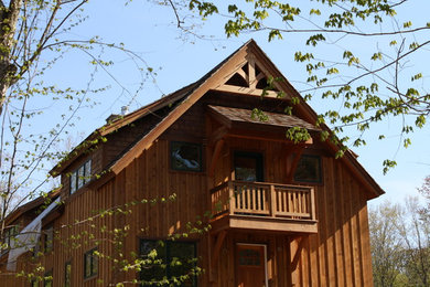 Imagen de fachada marrón clásica de dos plantas con revestimiento de madera