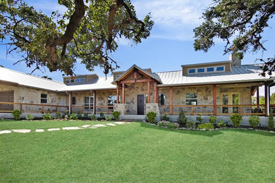 Example of a large mountain style beige one-story stone house exterior design in Austin with a shed roof and a metal roof