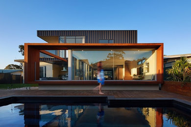 Ejemplo de fachada de casa marrón contemporánea grande de una planta con revestimiento de metal, tejado a dos aguas y tejado de metal
