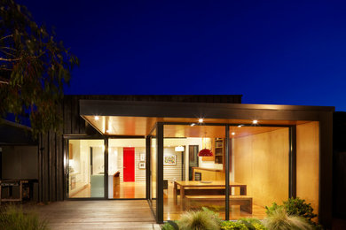 Inspiration pour une façade de maison noire minimaliste en bois de taille moyenne et de plain-pied avec un toit plat.