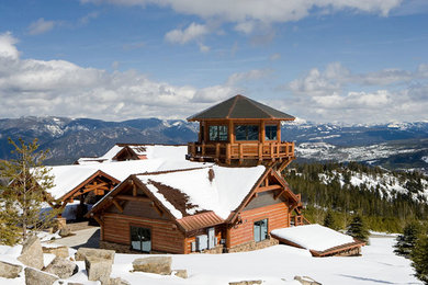 This is an example of a large rustic house exterior in Denver with three floors, wood cladding and a hip roof.