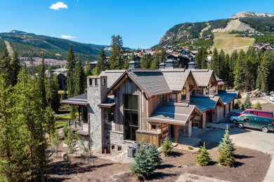 Large mountain style brown three-story wood exterior home photo in Other with a tile roof
