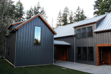 Ejemplo de fachada de casa negra de estilo de casa de campo de tamaño medio de dos plantas con revestimiento de madera, tejado a dos aguas y tejado de metal