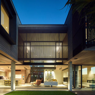 Inspiration for a contemporary two-storey beige house exterior in Sunshine Coast with wood siding and a flat roof.