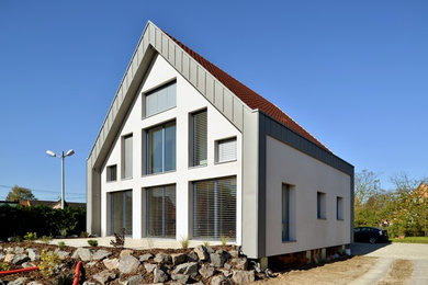 Idée de décoration pour une grande façade de maison blanche design à un étage avec un revêtement mixte et un toit à deux pans.