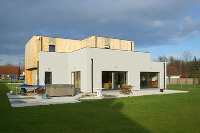 Cette image montre une grande façade de maison grise design en panneau de béton fibré à un étage avec un toit plat.