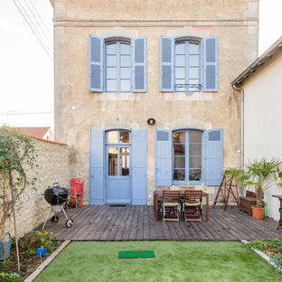 Cette image montre une façade de maison beige nordique à un étage avec un toit à quatre pans et un toit en shingle.