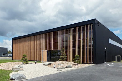 Ejemplo de fachada negra actual de dos plantas con revestimiento de madera y tejado plano