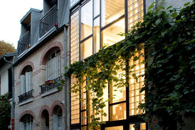 Idées déco pour une façade de maison de ville grise contemporaine en verre à deux étages et plus avec un toit plat.