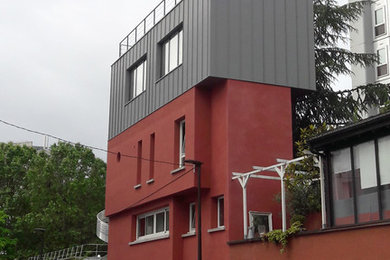 Cette image montre une petite façade de maison de ville métallique et grise design à deux étages et plus avec un toit plat et un toit mixte.