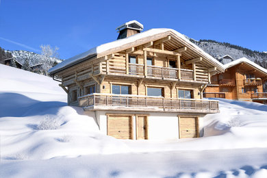Diseño de fachada de casa beige rústica grande de tres plantas con revestimiento de madera y tejado a dos aguas