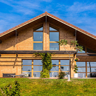 Réalisation d'une grand façade en bois marron chalet à un étage avec un toit à deux pans.