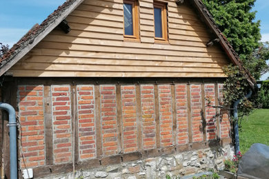 Cette image montre une petite façade de Tiny House multicolore rustique en bois et bardeaux à deux étages et plus avec un toit à deux pans, un toit en tuile et un toit rouge.