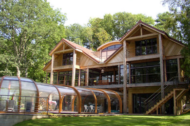 Réalisation d'une grande façade de maison marron design en bois et bardage à clin à deux étages et plus avec un toit à deux pans, un toit en tuile et un toit rouge.