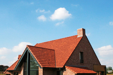 Modelo de fachada roja actual grande de dos plantas con revestimiento de ladrillo y tejado a la holandesa