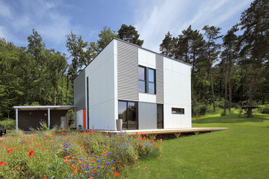 Idée de décoration pour une grande façade de maison grise design à un étage avec un revêtement mixte, un toit plat et un toit en métal.