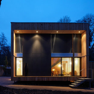 Idées déco pour une façade en verre noire contemporaine à un étage et de taille moyenne avec un toit plat.