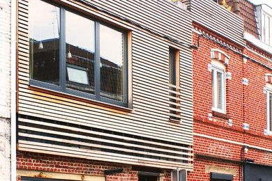 Réalisation d'une façade de maison rouge design en bois de taille moyenne et à deux étages et plus.