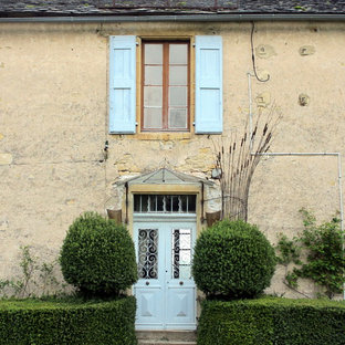 Exemple d'une façade de maison beige chic de taille moyenne et à un étage avec un revêtement en stuc et un toit à deux pans.