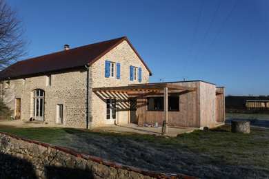 Cette photo montre une façade de maison nature en pierre de taille moyenne et à un étage avec un toit à deux pans.