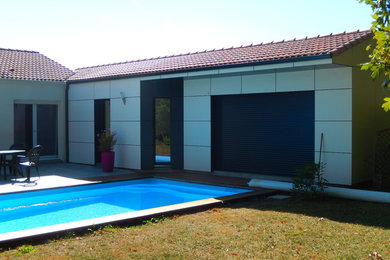 Diseño de fachada de casa blanca contemporánea de tamaño medio de una planta con revestimiento de aglomerado de cemento, tejado a dos aguas y tejado de teja de barro
