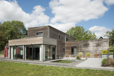 Cette photo montre une façade de maison grise moderne en bois de taille moyenne et de plain-pied avec un toit plat et un toit mixte.