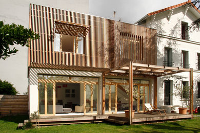 Cette image montre une grande façade de maison de ville design en bois à deux étages et plus avec un toit plat et un toit végétal.