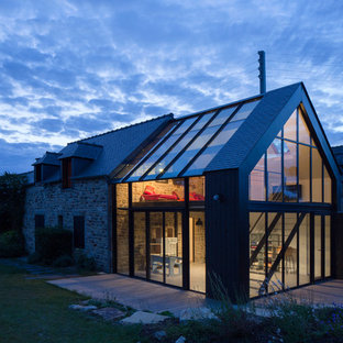 Aménagement d'une grand façade en verre beige contemporaine à un étage avec un toit à deux pans.