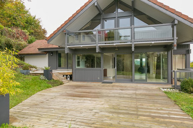 Idée de décoration pour une grande façade de maison grise design en bois à deux étages et plus avec un toit à quatre pans et un toit en tuile.