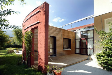 Cette image montre une grande façade de maison beige design en bois à deux étages et plus avec un toit à deux pans et un toit en tuile.