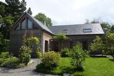 Cette photo montre une façade de maison marron nature en bois de taille moyenne et à un étage avec un toit à deux pans.