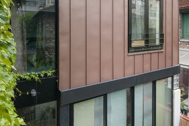 Idée de décoration pour une façade de maison marron minimaliste en verre de taille moyenne et à un étage avec un toit à deux pans.