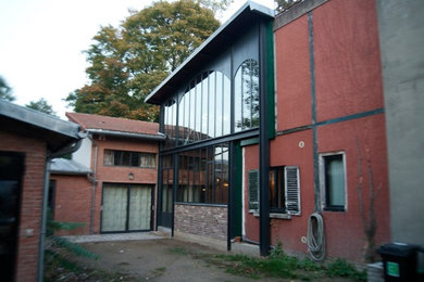 Esempio della facciata di una casa grande multicolore industriale a due piani con rivestimento in metallo e copertura in metallo o lamiera