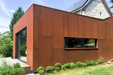 Inspiration pour une façade de maison métallique et marron design de taille moyenne et à deux étages et plus avec un toit plat et un toit en shingle.