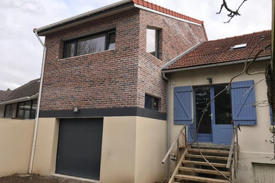 Esempio della facciata di una casa a schiera beige moderna a tre piani di medie dimensioni con rivestimento in mattoni, tetto a capanna e copertura in tegole