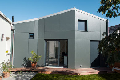 Idée de décoration pour une façade de maison métallique et grise design de taille moyenne et à un étage avec un toit à deux pans.
