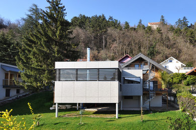 Réalisation d'une façade de maison grise design de taille moyenne et à deux étages et plus avec un revêtement mixte et un toit plat.