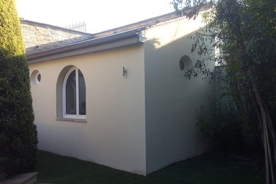 Idée de décoration pour une façade de maison beige minimaliste en béton de taille moyenne et à un étage avec un toit à deux pans.