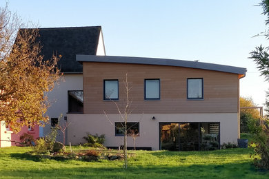Cette image montre une façade de maison beige minimaliste en bois de taille moyenne et à un étage avec un toit en métal.