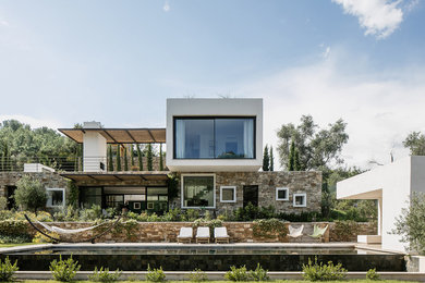 Cette photo montre une grande façade de maison multicolore tendance en stuc à un étage avec un toit plat.