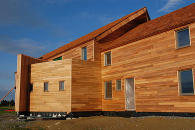 Idée de décoration pour une façade de maison marron design en bois avec un toit de Gambrel.