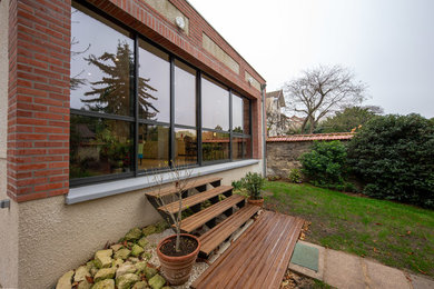 Cette photo montre une façade de maison marron tendance en brique de taille moyenne et de plain-pied avec un toit plat.
