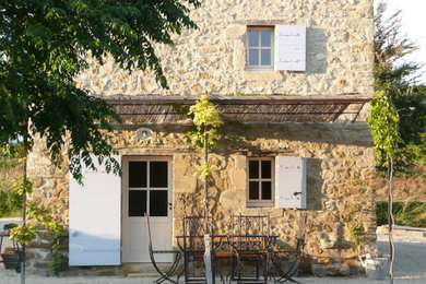 Cette image montre une façade de maison beige rustique en pierre de taille moyenne et à un étage.