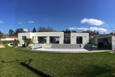 Cette photo montre une façade de maison blanche tendance en béton de taille moyenne avec un toit plat et un toit mixte.