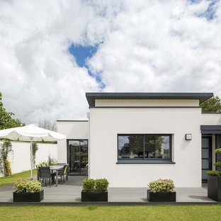 Cette photo montre une façade de maison blanche tendance de plain-pied avec un revêtement en stuc et un toit plat.