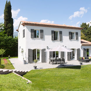 Aménagement d'une façade de maison blanche méditerranéenne à un étage et de taille moyenne avec un toit à deux pans et un toit en tuile.